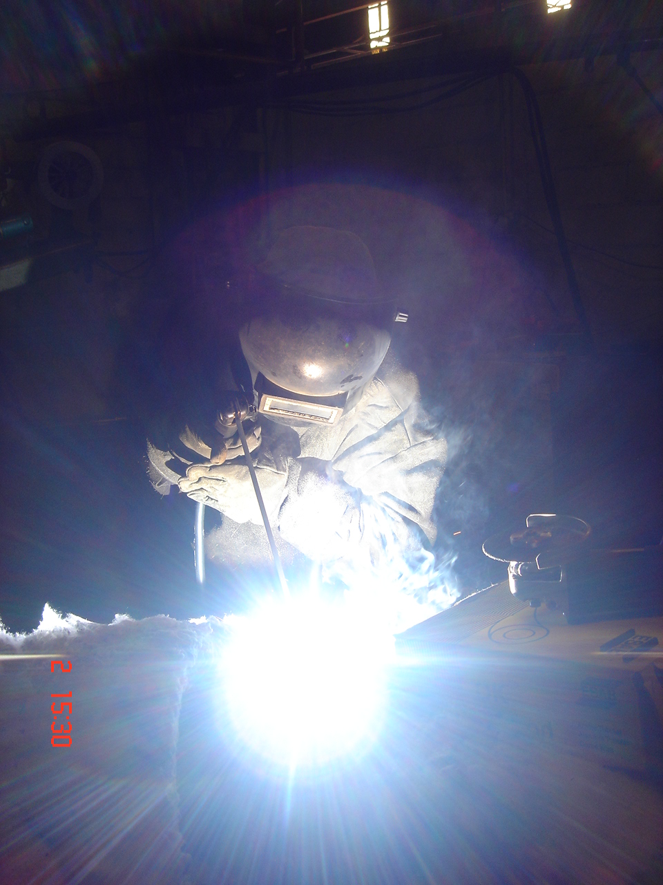 Soldador clássico com equipamento de proteção durante soldagem industrial